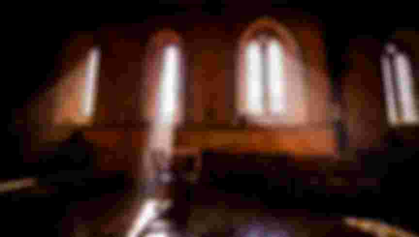 Rays of sunshine streaming through the leaded-light windows in an empty church. Credit: Jim Holden / Alamy Stock Photo.