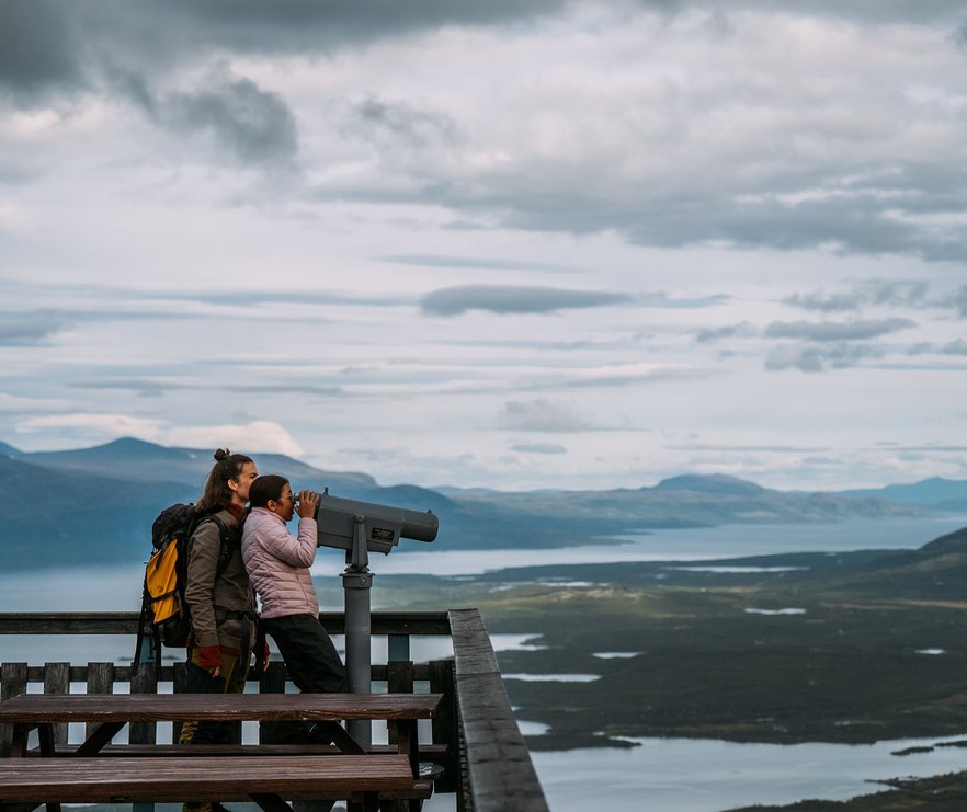en mor med sin dotter spanar i den stora kikaren p&aring; naturen i Abisko