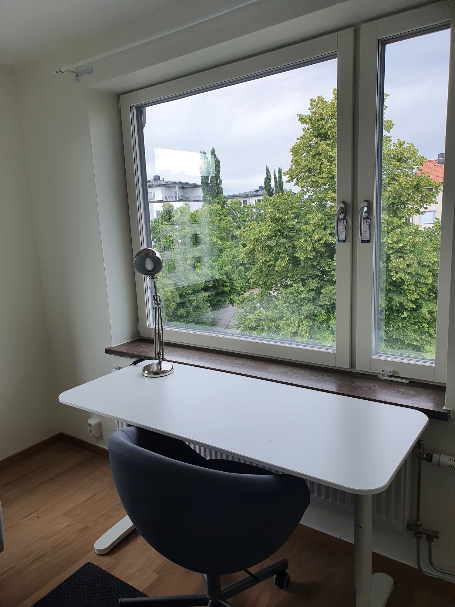 Desk and chair in front of window with view over trees.