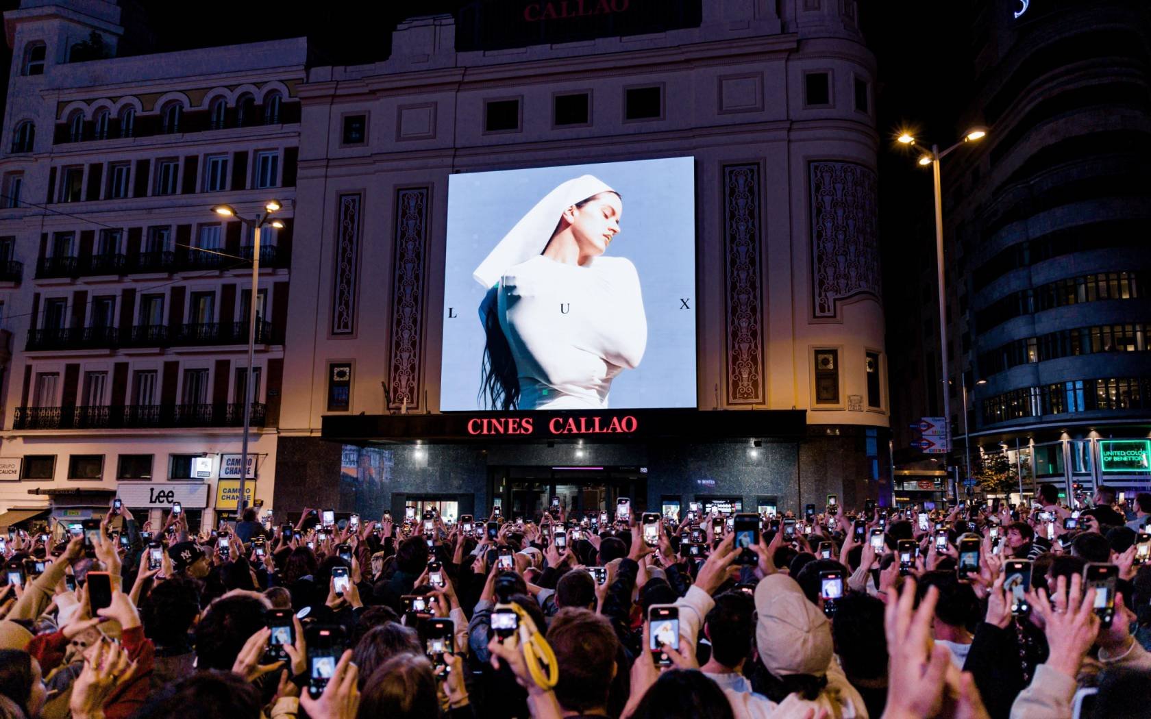 A crowd looks at the cover of Rosalia's new album, 'Lux', in Madrid.