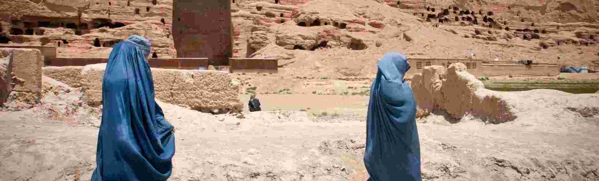 Two Afghan women walk past the cavity where one of the ancient Buddhas of Bamiyan used to stand