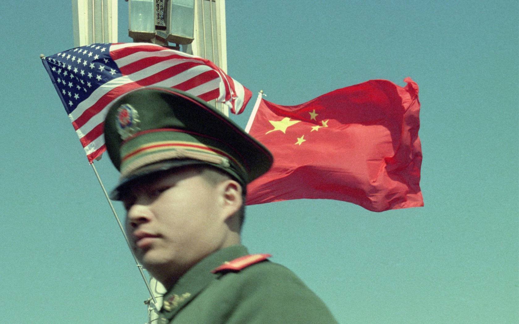 A policeman stands in front of Chinese and American flags during a visit by George W. Bush to China, 2002.