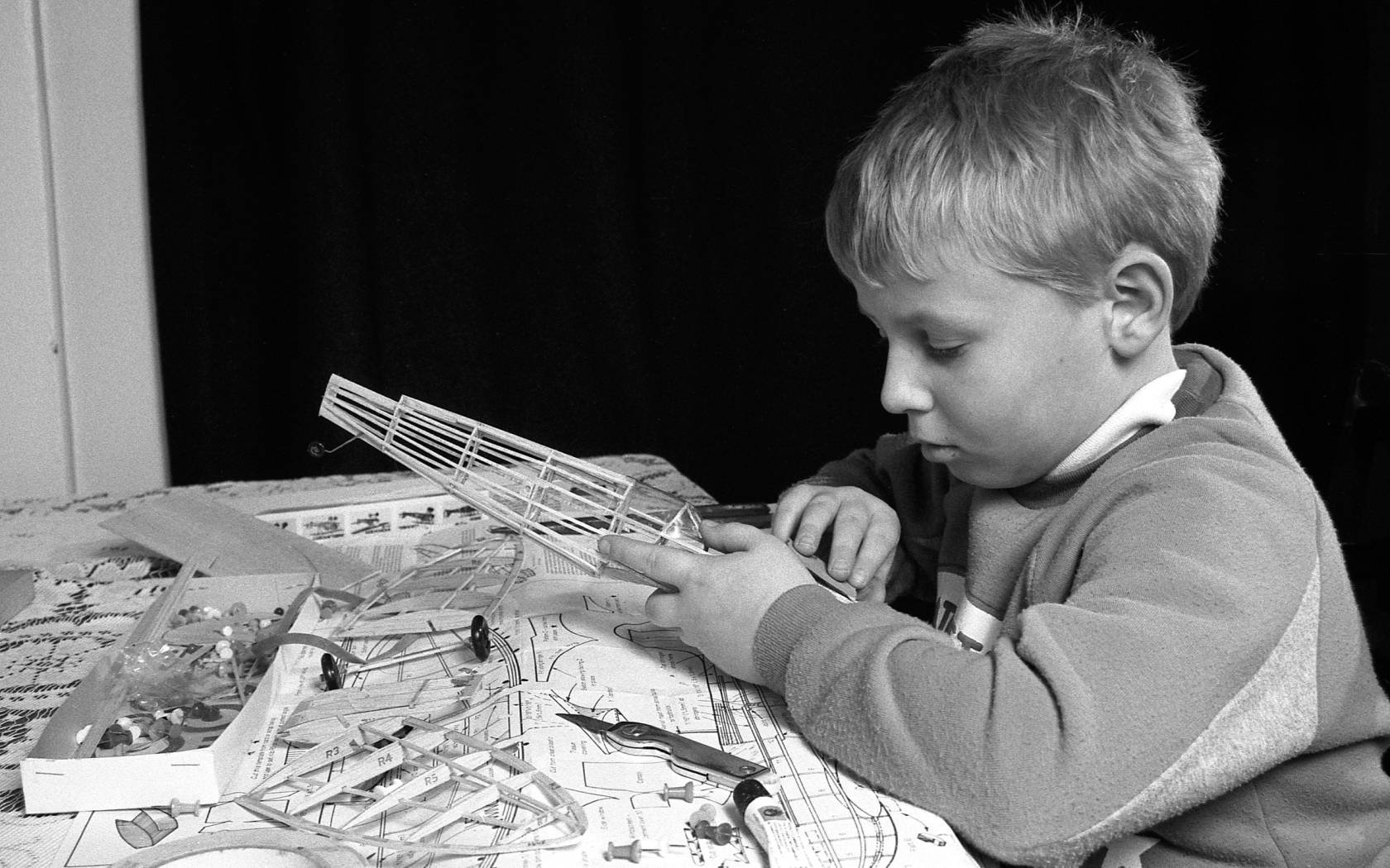 Young boy building balsa wood scale model aeroplane.
