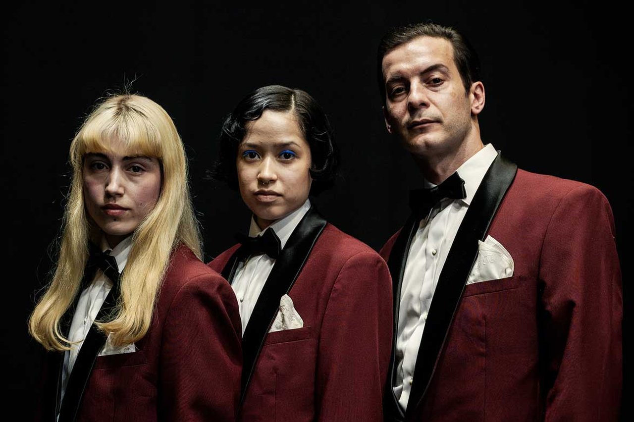 Tre personer i röd smoking från föreställningen Burn Baby Burn.