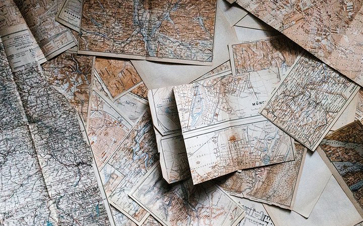 Massor av gamla kartor ligger på ett bord.