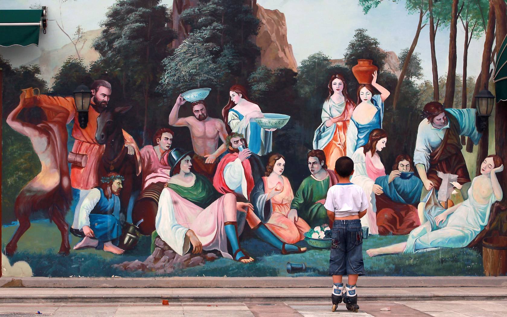 A young Chinese boy on skates stops to check out a newly painted mural depicting ancient Roman and Greek motifs at a new, international shopping plaza in Beijing on July 7, 2013.