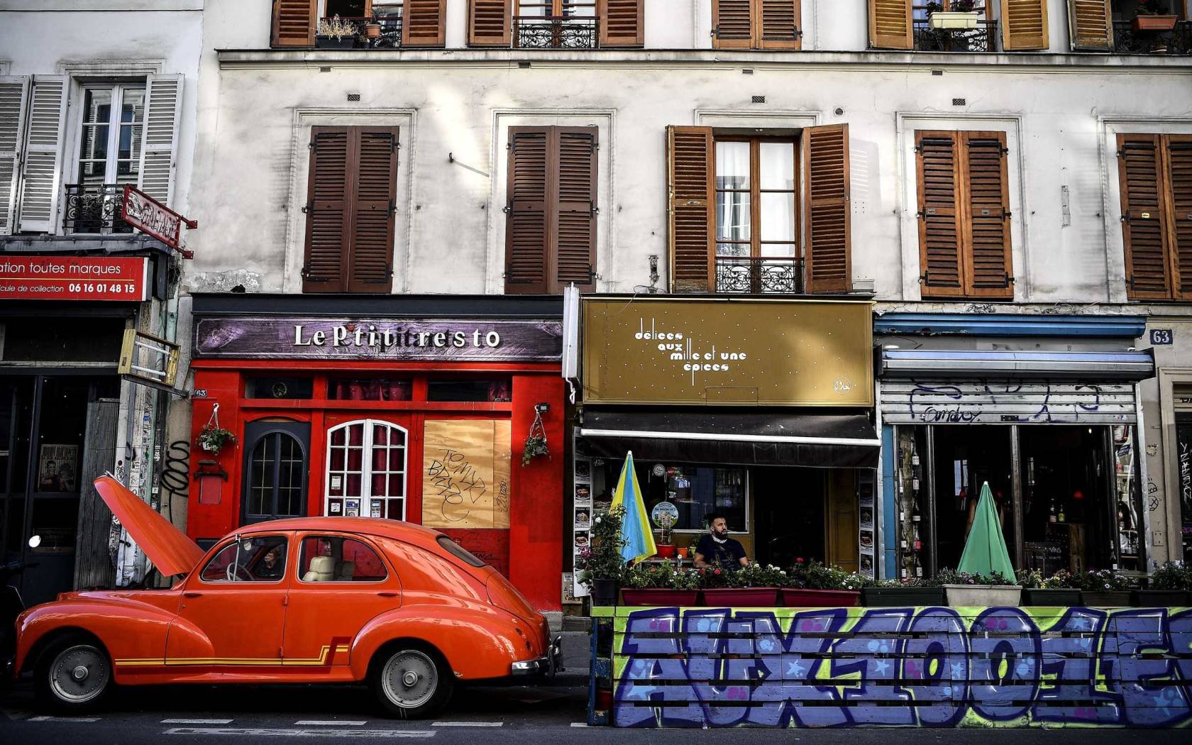 A man sits on an extended terrace made of wooden pallets in Paris