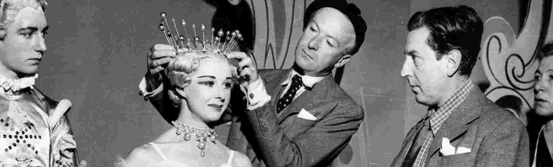 Cecil Beaton adjusting a headpiece backstage.