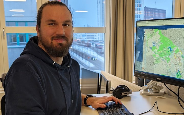 Jonas Rinnbäck står vid sin dator på kontoret. På skärmen syns en karta.