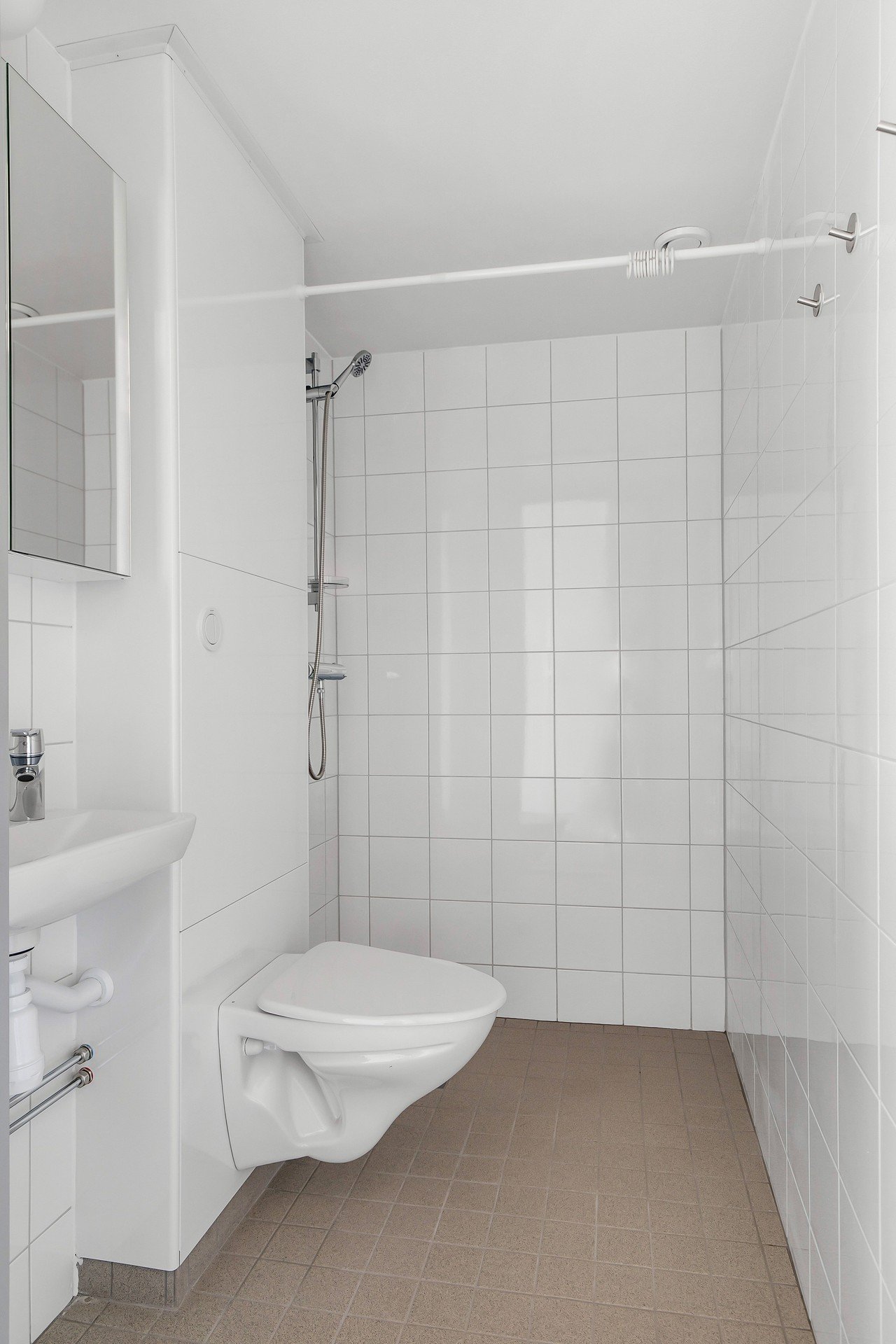 White tiled bathroom with sink, wc and shower.