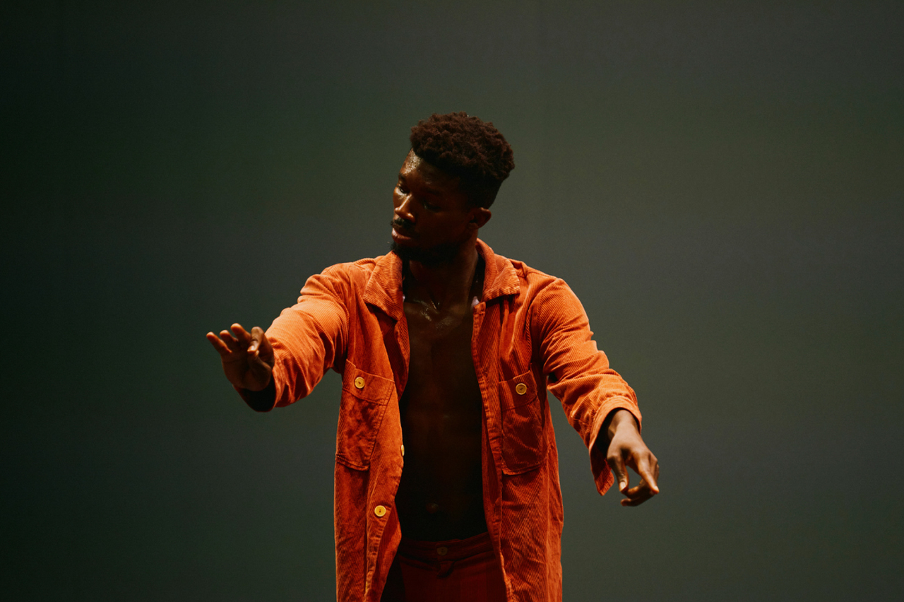 Dansaren står på scen med händerna i rörelse.