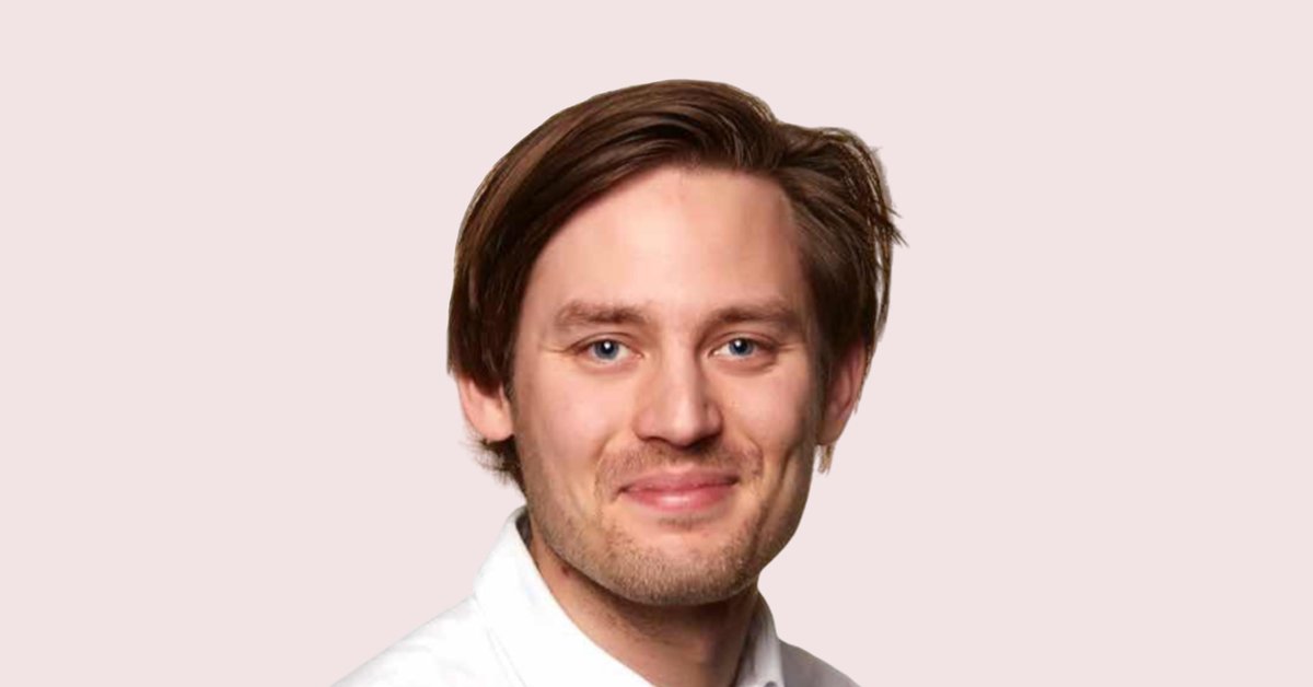 A close-up of Johannes Löfgren who’s wearing a white shirt and standing in front of a light pink background.