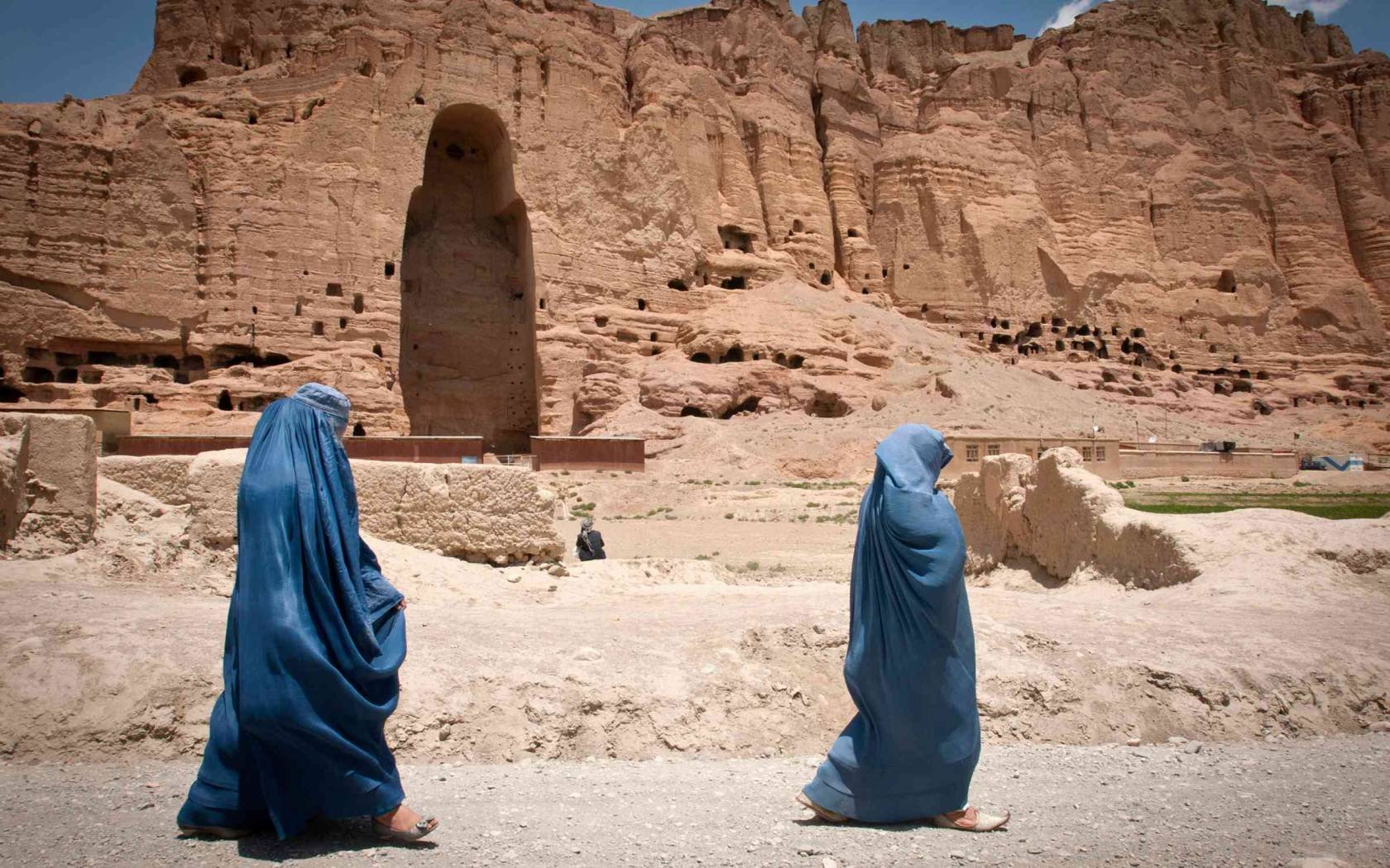 Two Afghan women walk past the cavity where one of the ancient Buddhas of Bamiyan used to stand