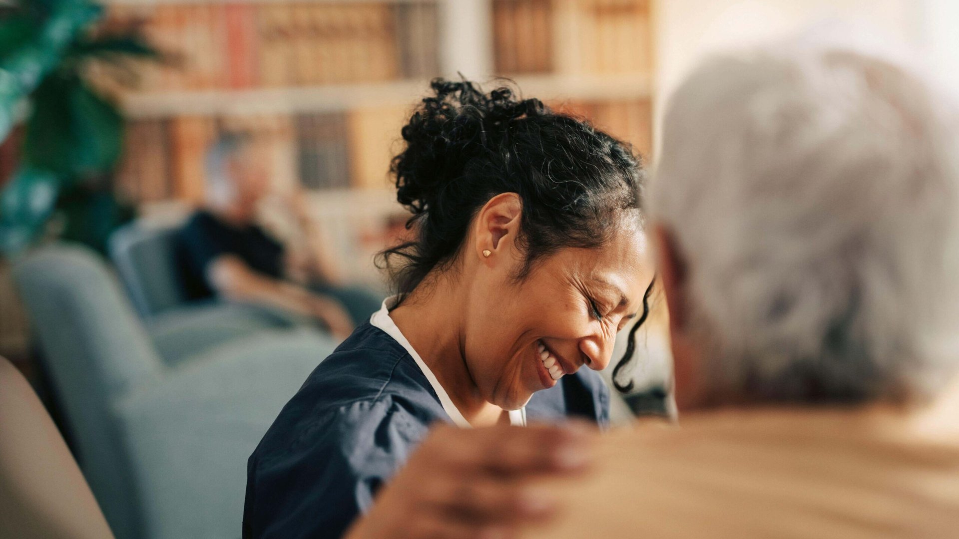 Smiling female nursing assistant with hand on shoulder of senior patient at retirement home