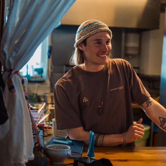 en kille i personalen ler bakom kassan