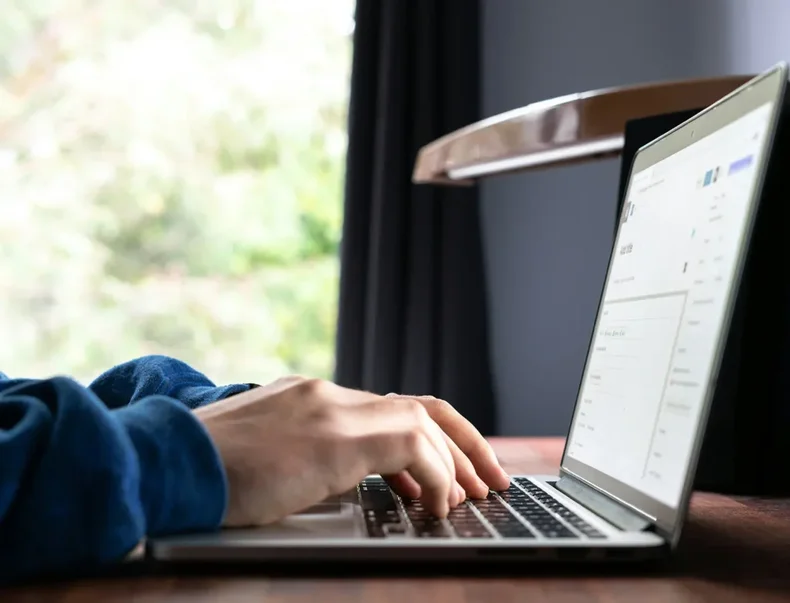 En person skriver ett mejl på sin dator.