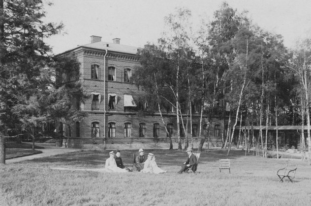 Sköterskeelever sitter i gräset på Sophiahemmets baksida, 1890.