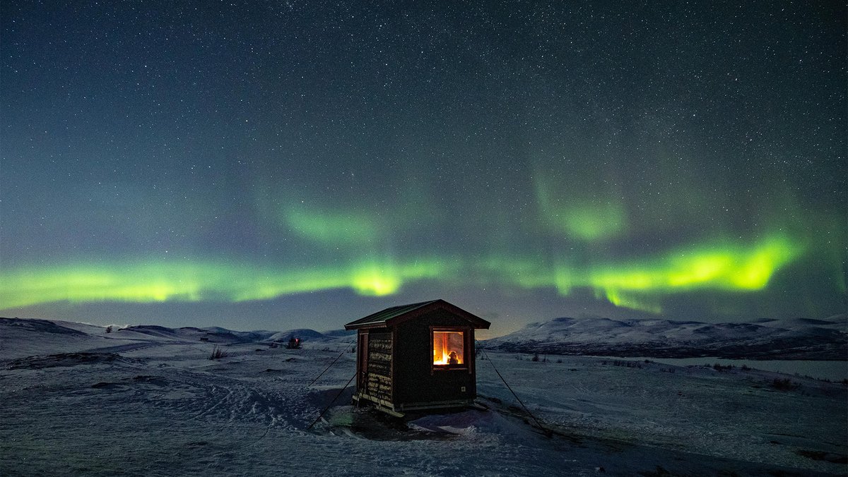 utsiktsstuga på fjället under det dansande norrskenet