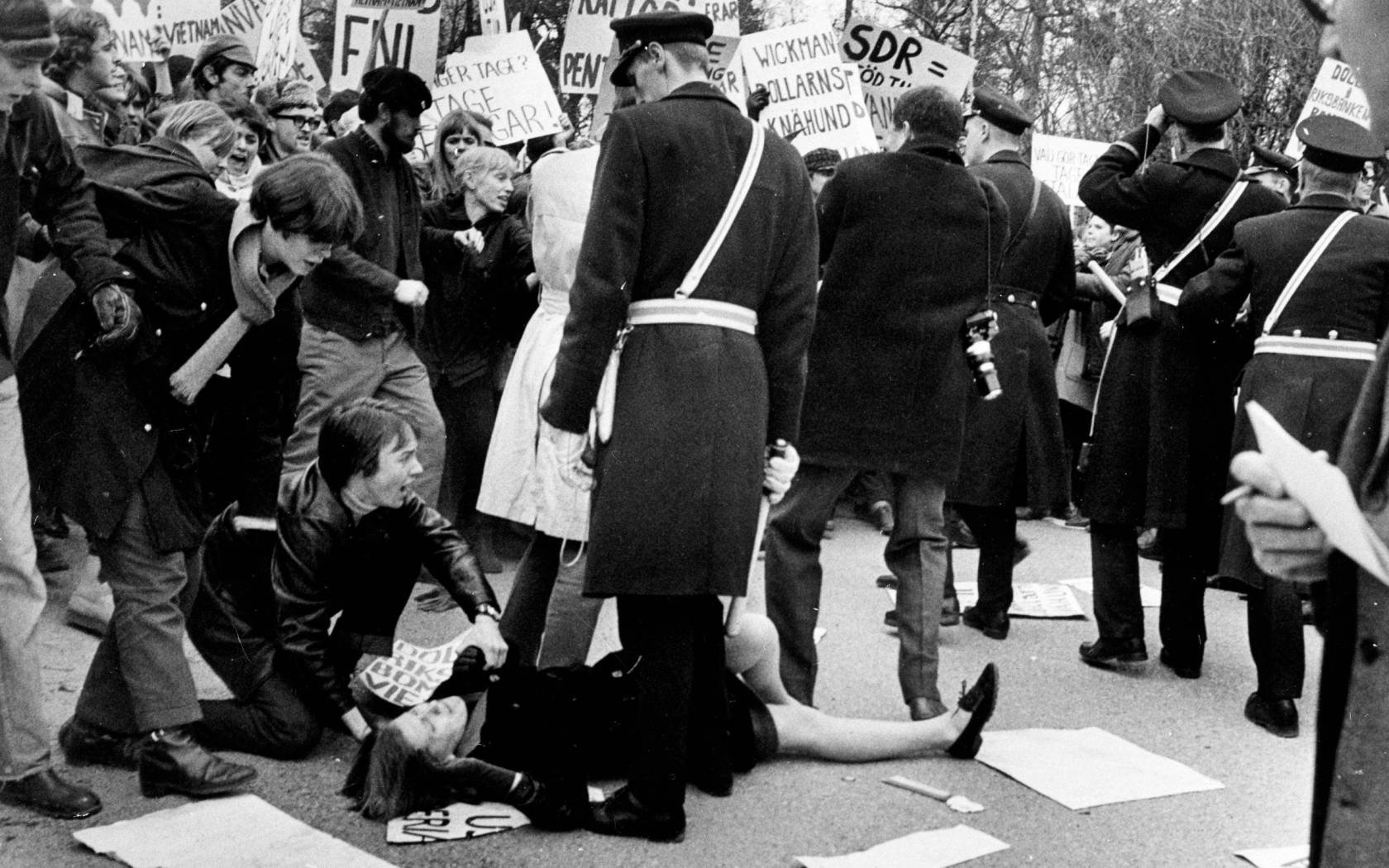 A terre, une jeune femme lors de la manifestation étudiante contre la guerre au Vietnam, à Stockholm, Suède le 1 avril 1968.