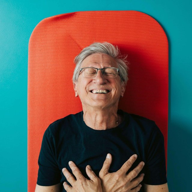Directly above shot of happy man with hands on chest lying on exercise mat